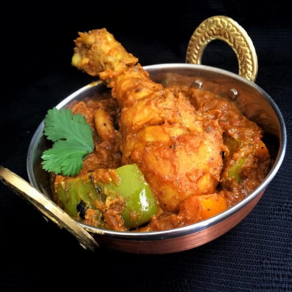 Kadhai Indian Cuisine's chicken curry with green peppers and cilantro in a copper serving dish.