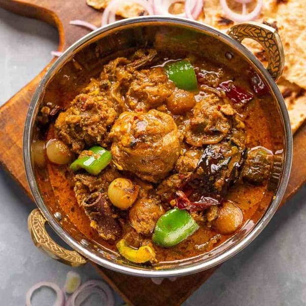 Kadhai Indian Cuisine's chicken curry with green peppers and onions in a metal bowl.