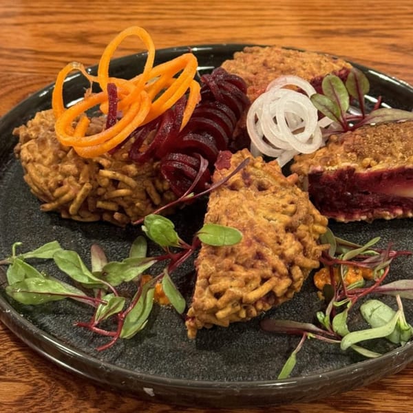 Indian appetizer with crispy fried pieces, sliced beets, carrots, and onions, garnished with microgreens.